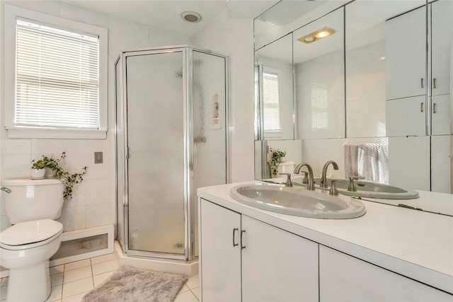 bathroom with toilet, vanity, tile patterned flooring, tile walls, and walk in shower