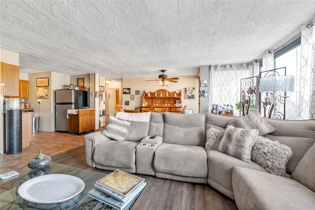 living room with a textured ceiling, wood-type flooring, and ceiling fan