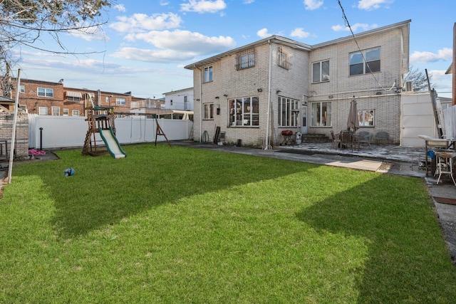 back of property with a patio, a yard, and a playground