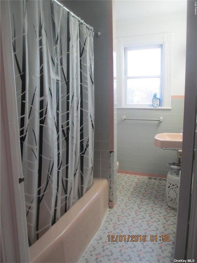 bathroom with tile walls and shower / bath combination with curtain