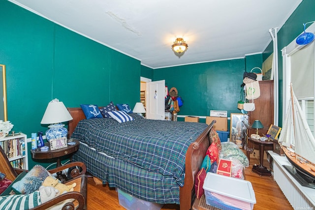 bedroom with ornamental molding and hardwood / wood-style flooring