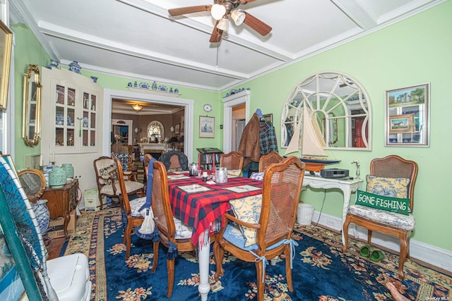 dining room with ceiling fan, beam ceiling, ornamental molding, and a fireplace