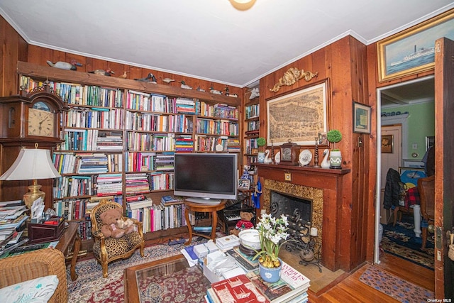 living area with wood walls, crown molding, and hardwood / wood-style floors