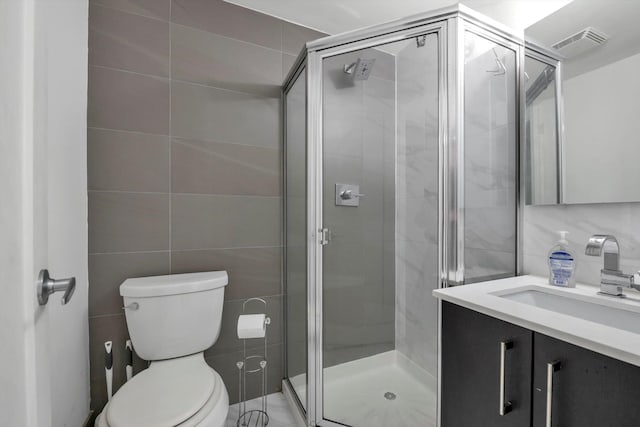 bathroom featuring vanity, a shower with shower door, tile walls, and toilet