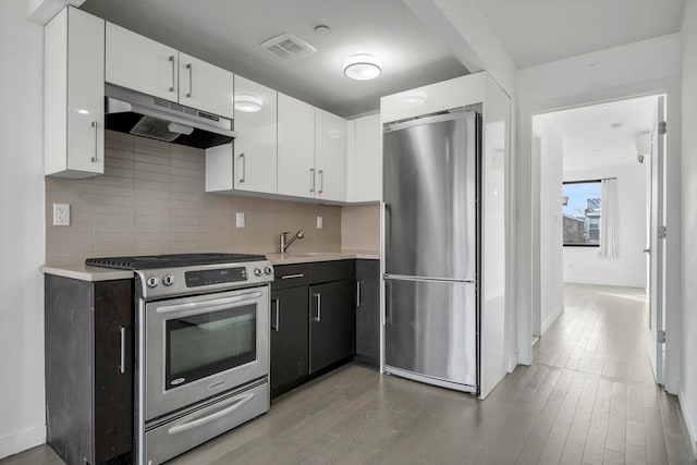 43-12 214th Pl Unit 2A, Bayside, NY 11361 - kitchen with under cabinet range hood, light countertops, white cabinetry, and stainless steel appliances