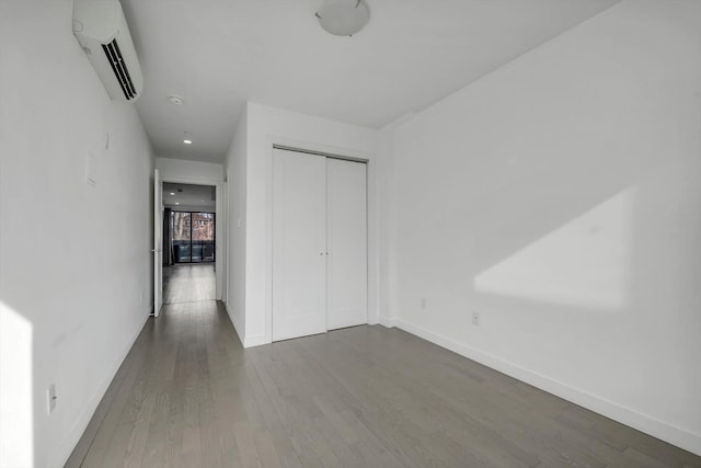 43-12 214th Pl Unit 2A, Bayside, NY 11361 - unfurnished bedroom featuring a wall mounted air conditioner, baseboards, a closet, and wood finished floors