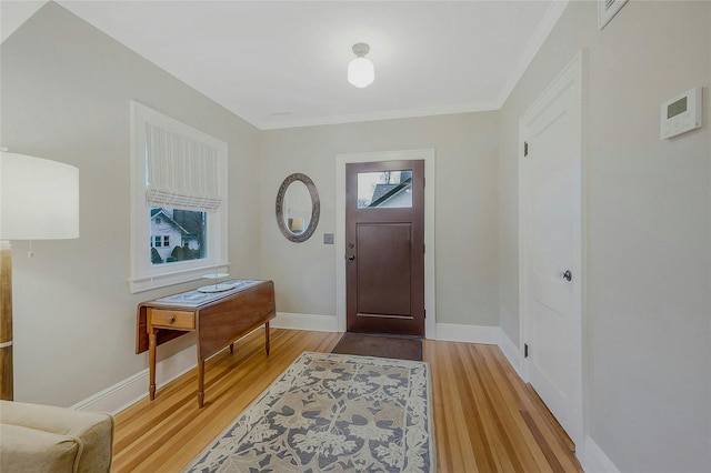 foyer entrance with light hardwood / wood-style floors and ornamental molding