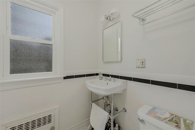 bathroom featuring sink, tile walls, toilet, and radiator