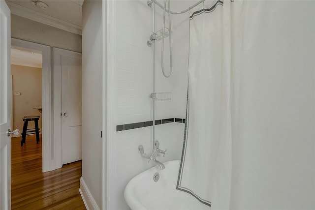 bathroom with hardwood / wood-style flooring, ornamental molding, and shower / bathtub combination with curtain