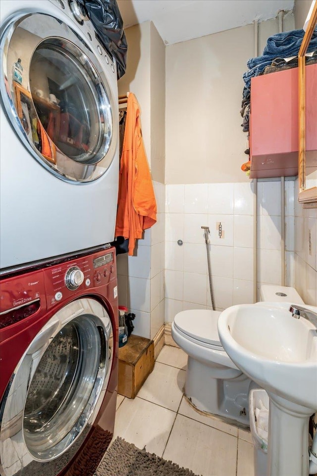 bathroom featuring tile walls, stacked washer / drying machine, toilet, and tile patterned flooring