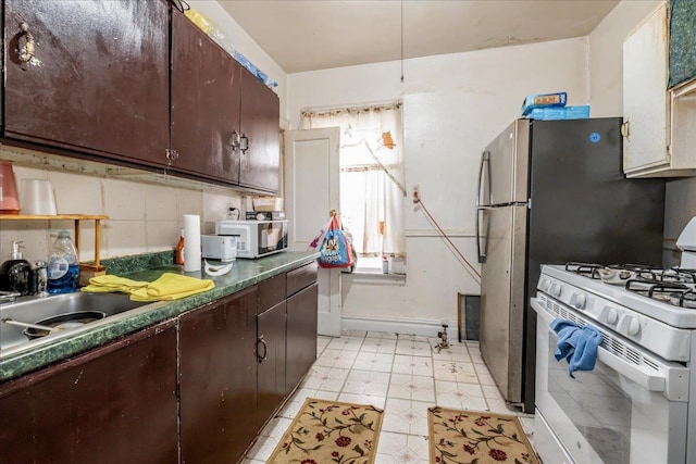 kitchen with decorative backsplash, sink, dark brown cabinetry, and white gas stove