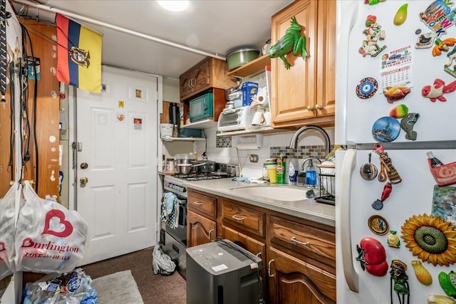 kitchen with high end stainless steel range, decorative backsplash, sink, and white fridge