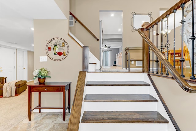 staircase with ceiling fan and carpet floors