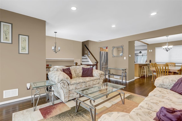 living room featuring ceiling fan with notable chandelier and wood-type flooring