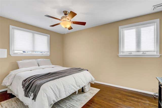 bedroom with ceiling fan, dark hardwood / wood-style flooring, and multiple windows