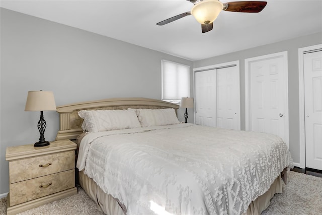 carpeted bedroom featuring ceiling fan and two closets