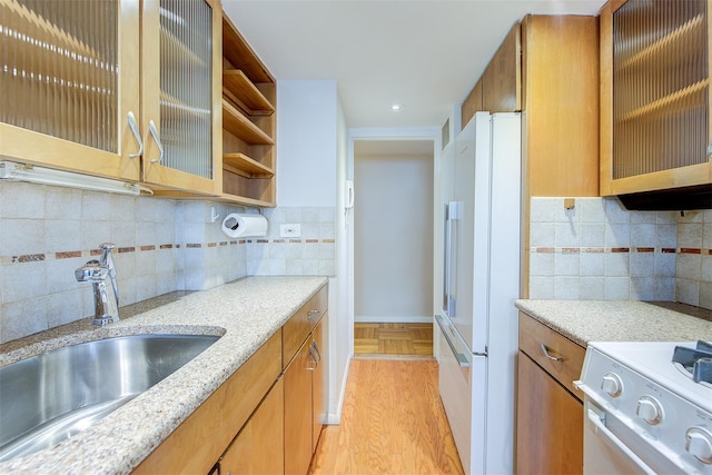 kitchen with backsplash, white appliances, light hardwood / wood-style flooring, and sink