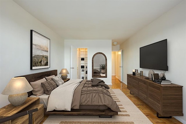 bedroom featuring light parquet flooring and a walk in closet