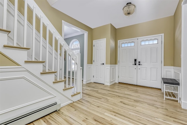 entryway featuring a baseboard heating unit, crown molding, and light hardwood / wood-style floors