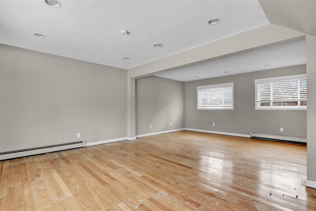 spare room featuring baseboard heating and light hardwood / wood-style flooring