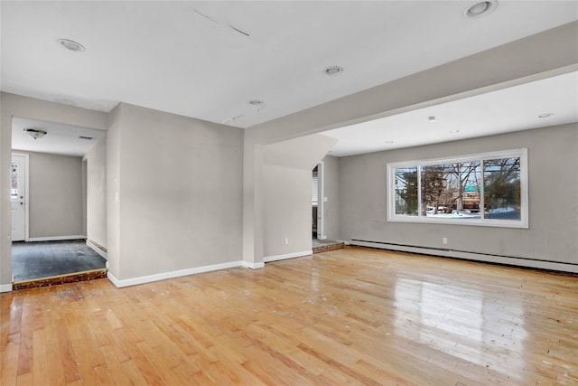 unfurnished living room featuring baseboard heating and light hardwood / wood-style floors