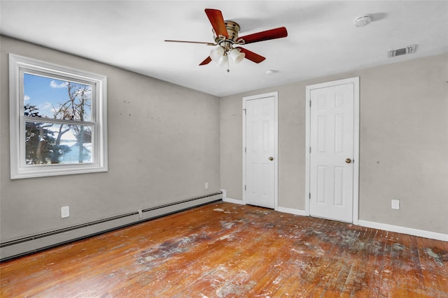 unfurnished bedroom featuring ceiling fan, a baseboard radiator, wood-type flooring, and two closets