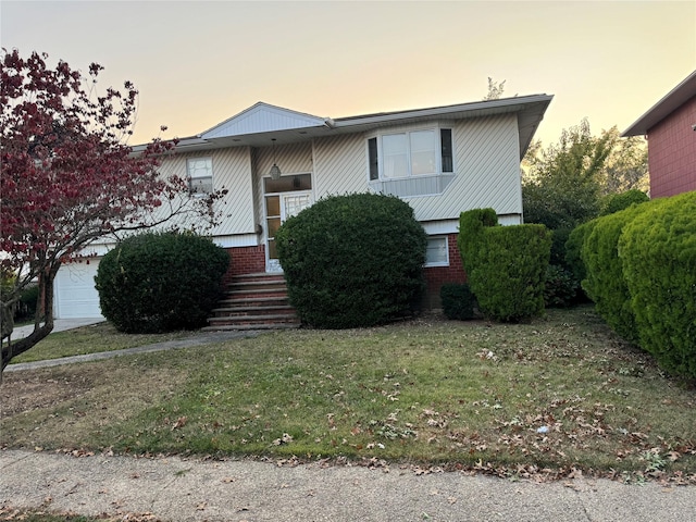 split foyer home with a garage and a yard