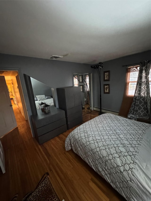 bedroom with dark hardwood / wood-style flooring and baseboard heating