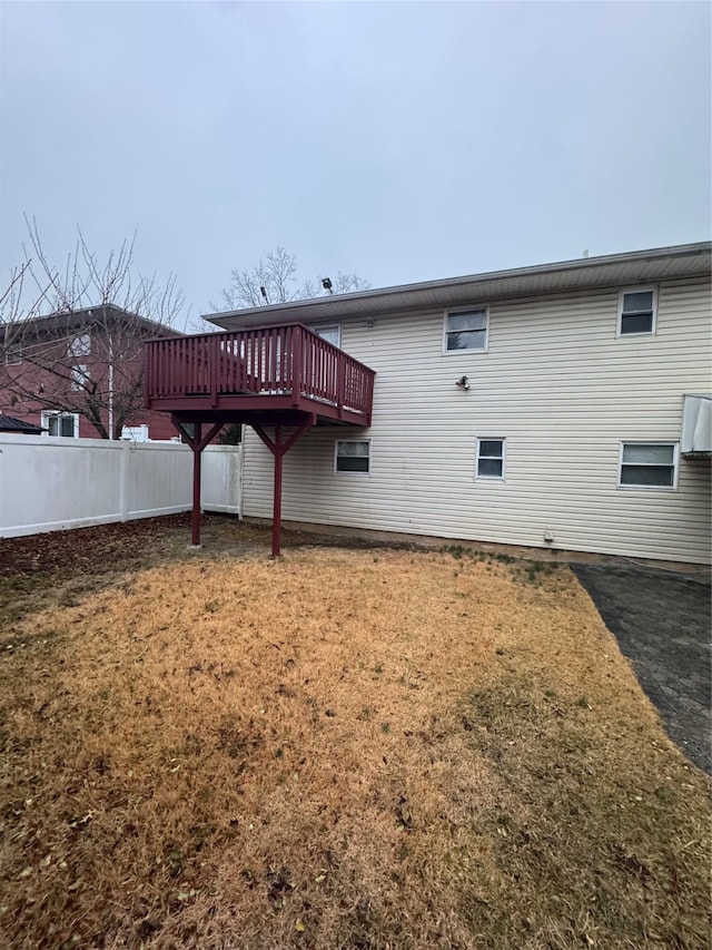 back of property featuring a wooden deck and a lawn