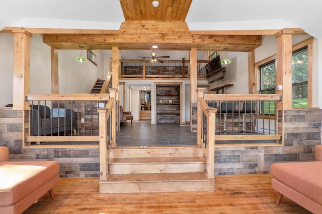 staircase with ceiling fan, a healthy amount of sunlight, wood ceiling, and hardwood / wood-style floors