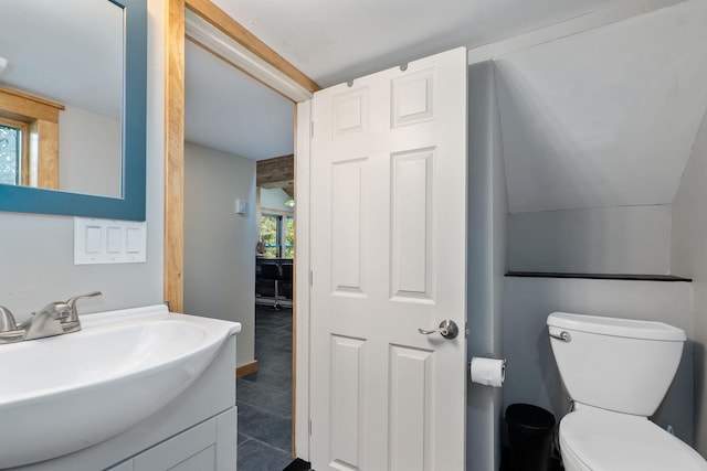 bathroom featuring toilet, vanity, and vaulted ceiling