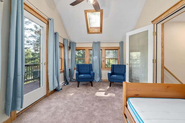 carpeted bedroom featuring ceiling fan, vaulted ceiling with skylight, and access to outside