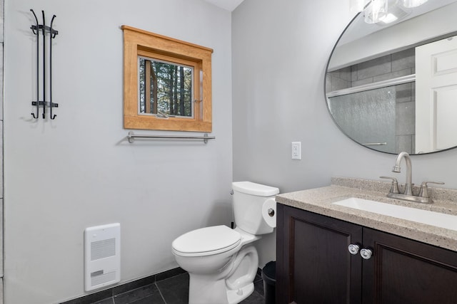 bathroom featuring toilet, vanity, tile patterned flooring, walk in shower, and heating unit