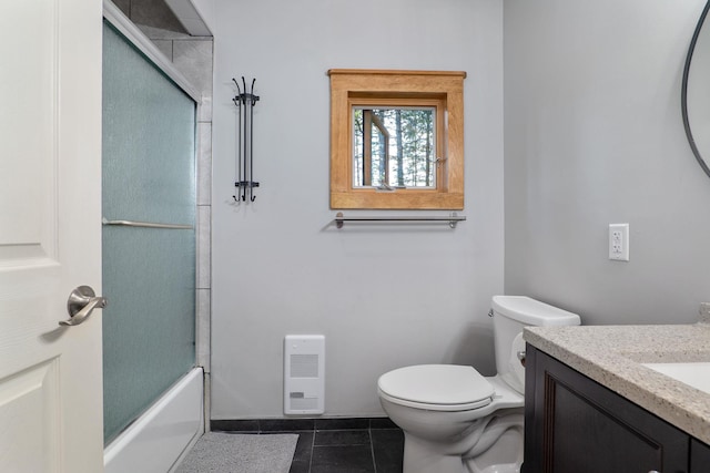 full bathroom featuring toilet, vanity, tile patterned flooring, and bath / shower combo with glass door