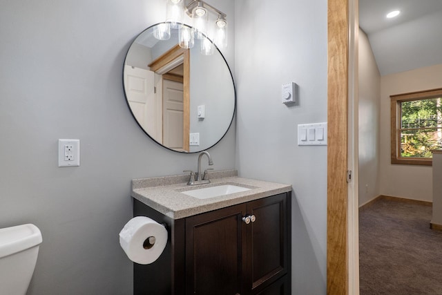 bathroom with toilet, vanity, and vaulted ceiling