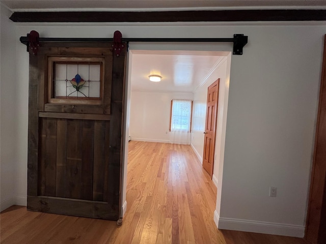 hall featuring light hardwood / wood-style flooring, ornamental molding, and a barn door