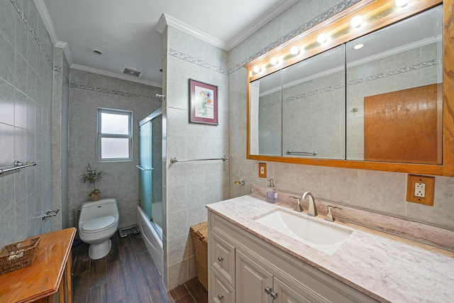 full bathroom featuring shower / bath combination with glass door, vanity, tile walls, toilet, and crown molding