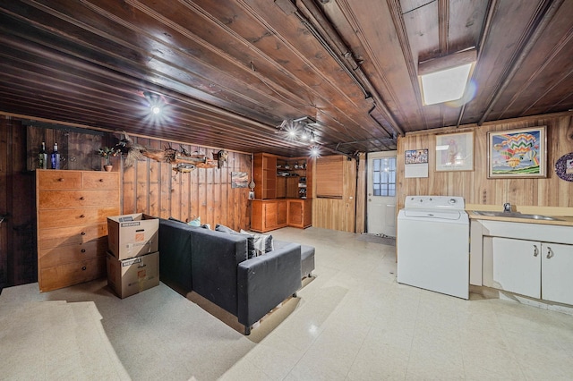 basement featuring washer / clothes dryer, sink, wood walls, and wooden ceiling