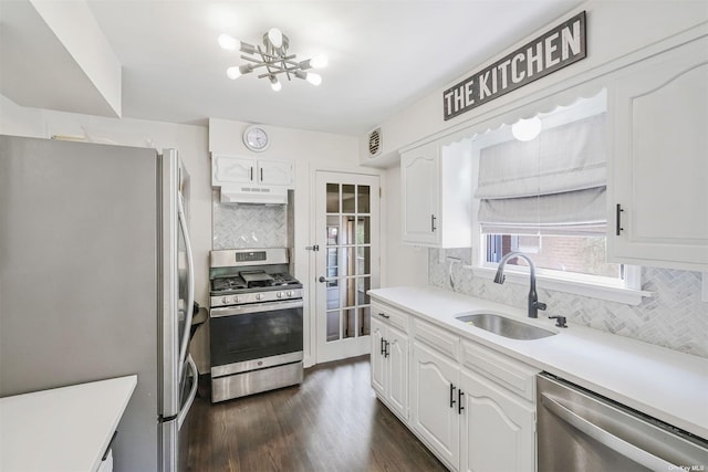 kitchen featuring appliances with stainless steel finishes, decorative backsplash, a chandelier, white cabinets, and sink