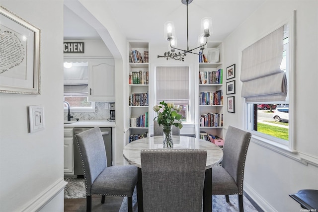 dining area with sink, built in features, and an inviting chandelier