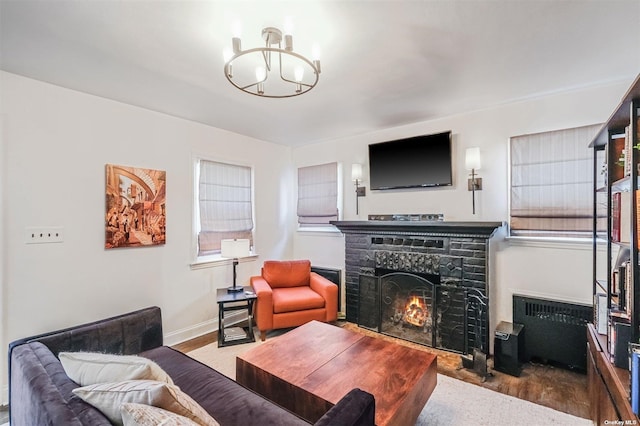 living room with wood-type flooring, a fireplace, and a notable chandelier