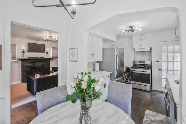 dining space featuring a brick fireplace, dark hardwood / wood-style floors, and an inviting chandelier