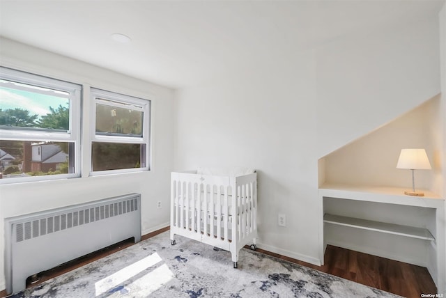 bedroom featuring hardwood / wood-style flooring and radiator heating unit