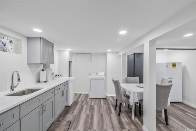 kitchen with washing machine and dryer, sink, light hardwood / wood-style flooring, gray cabinetry, and white refrigerator