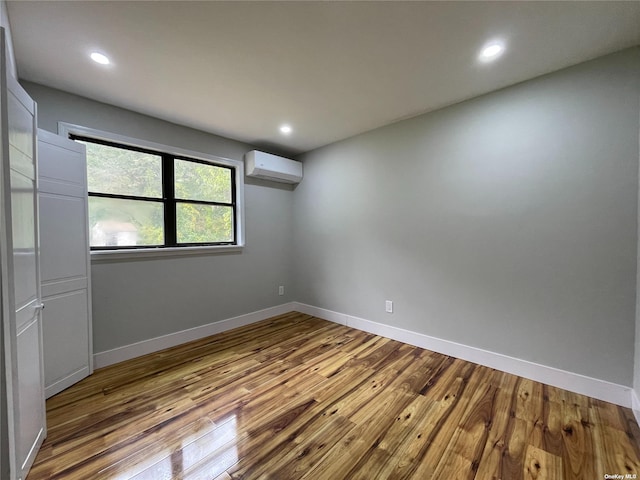 unfurnished room with light wood-type flooring and an AC wall unit