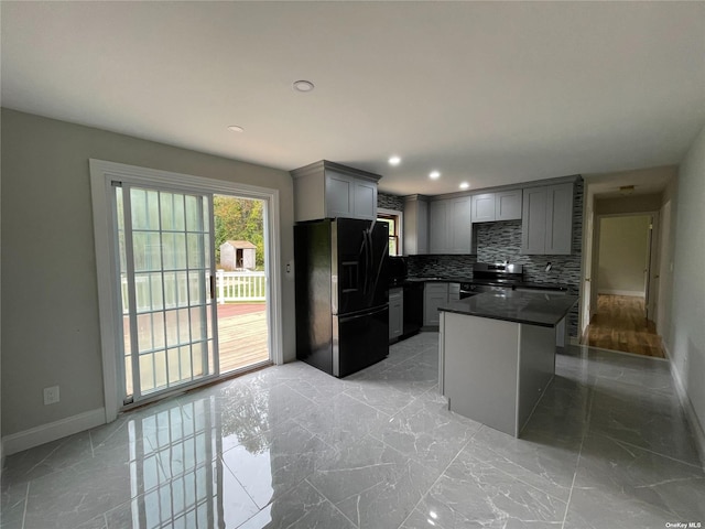 kitchen featuring backsplash, gray cabinets, a kitchen island, black appliances, and a kitchen bar