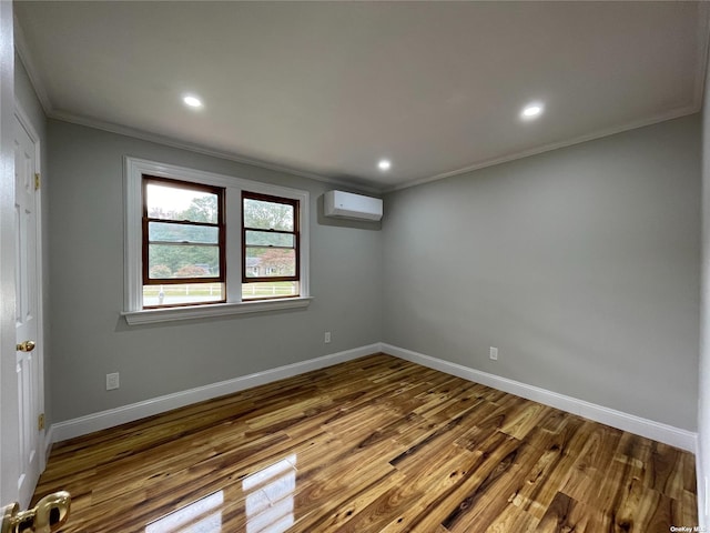 empty room with ornamental molding, hardwood / wood-style flooring, and an AC wall unit