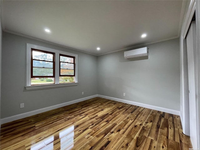 spare room with an AC wall unit, crown molding, and hardwood / wood-style flooring