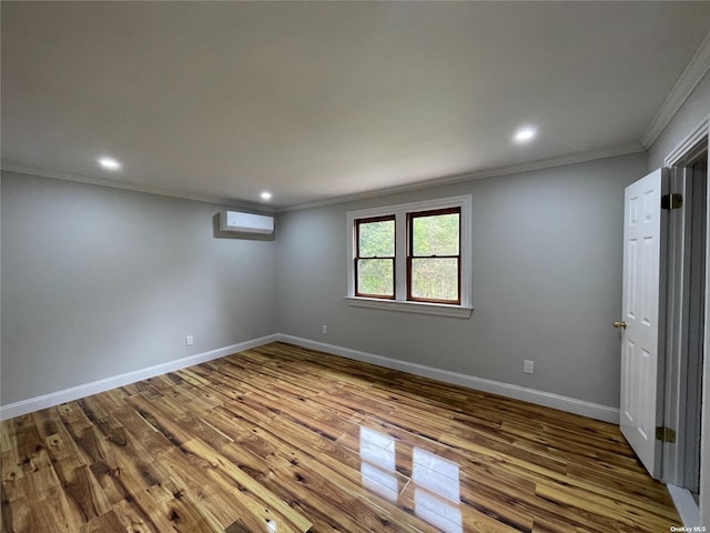 unfurnished room featuring crown molding, hardwood / wood-style flooring, and a wall mounted air conditioner