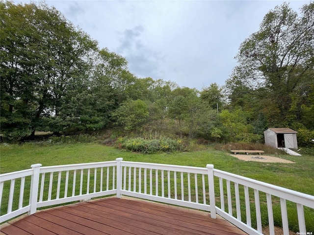 wooden deck featuring a shed and a lawn